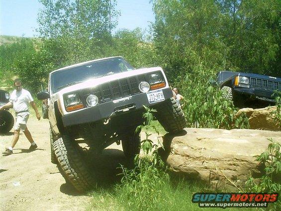 White Jeep Cherokee XJ climbing over a rock, license plate 372-HFH