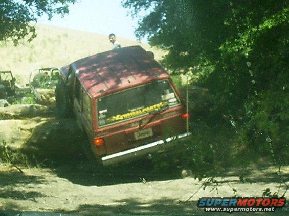 red Jeep Cherokee driving off-road, another vehicle behind it