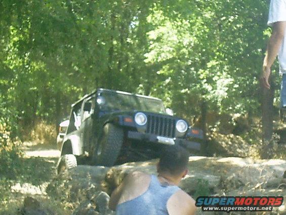 Black Jeep Wrangler TJ climbing over rocks on a dirt trail