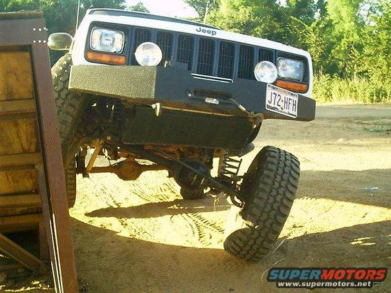 White Jeep with aftermarket bumper and off-road tires, front passenger side wheel at an angle