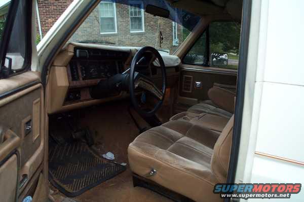 Interior view of a 1985 Ford Bronco showing dashboard, steering wheel, and tan seats