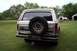 1985 Ford Bronco - Rear view of a 1985 Ford Bronco, showing its spare tire and a distant pickup truck.