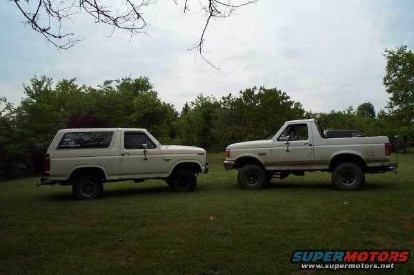 Two white Ford Broncos parked on grass, one is a Bronco SUV and the other is a Bronco pickup truck