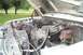 1985 Ford Bronco - The engine bay of a white truck is shown with the hood raised, revealing various mechanical components and wiring.