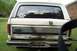 1985 Ford Bronco - The rear of a white Ford Bronco, with visible rust on the lower tailgate and bumper.