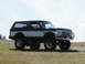 1994 Ford Bronco - A lifted Ford Bronco sits on a grassy hill under a clear blue sky.