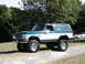 1994 Ford Bronco - Lifted 1990s Ford Bronco parked outdoors with a Chevrolet Corvette in the background.