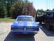 1968 Ford Mustang - Rear view of a blue 1967 Ford Mustang coupe with racing stripes parked next to a dark SUV.