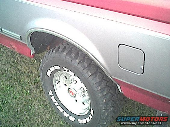 Two-tone silver and red Ford Bronco rear fender with a mud-terrain tire and chrome wheel