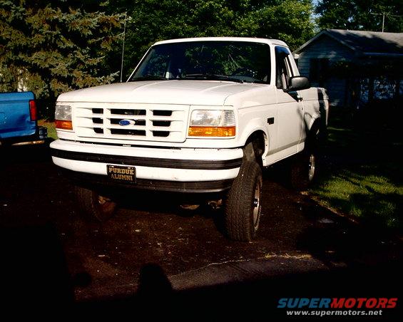 White Ford F-150 pickup truck parked in driveway, Purdue Alumni plate on front