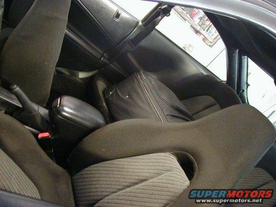 Car interior with dark fabric seats, a center console, and a black suitcase behind the seats