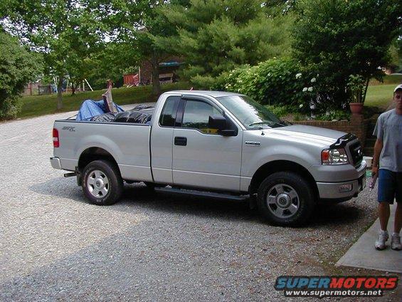 Silver pickup truck with a short bed and a man standing nearby