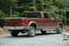 2006 Ford F-350 - This pickup truck is parked on a gravel lot surrounded by trees, showing its rear and side profile.