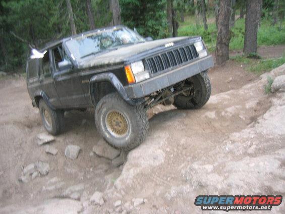 1997 Jeep Cherokee navigating a rocky trail with front wheel lifted