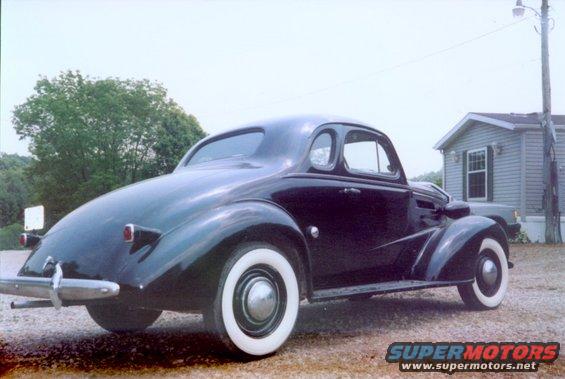 Dark coupe with whitewall tires, rear view