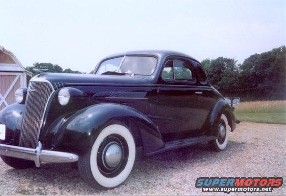 1937 Chevrolet Coupe parked on gravel with a barn in the background