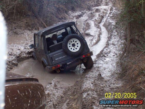 Suzuki Samurai stuck in mud, rear view, spare tire visible on back