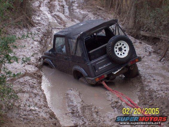 Black Suzuki Samurai stuck in mud, rear view with tow rope