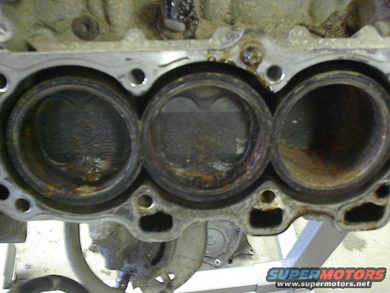 Close-up of three engine cylinders, showing wear and rust