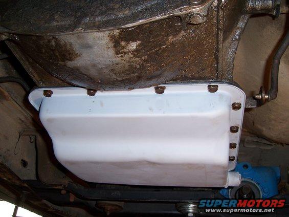 underside view of a transmission oil pan with bolts and a blue component underneath