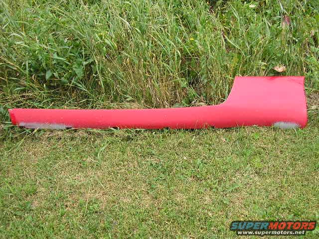 Red car door sill trim piece on grass