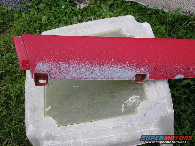 Red plastic car door edge trim piece with primer showing through chipped paint