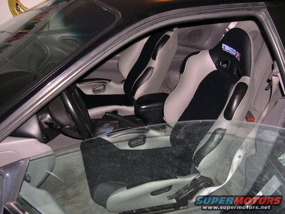 Interior view of a car with racing bucket seats, a steering wheel, and center console
