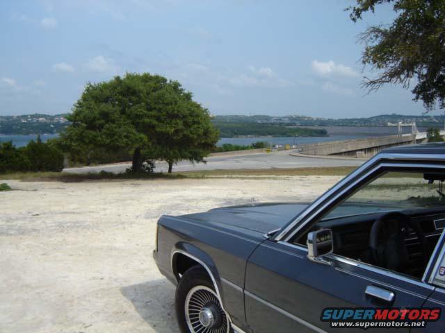 1988 Ford Crown Victoria LTD parked near a lake with a bridge in the background