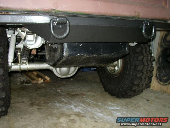 Rear axle, fuel tank, and large off-road tires visible on a vehicle