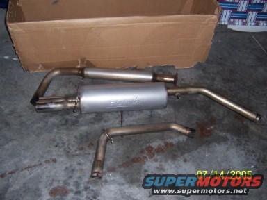 Exhaust system parts laid out on a concrete floor, with a cardboard box in the background