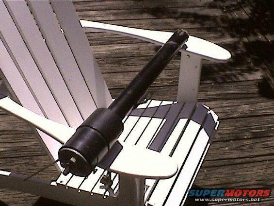 Black steering column part resting on a white Adirondack chair