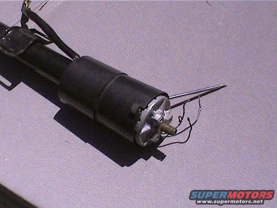 Close-up of a black steering column assembly with exposed wires and a metal rod extending from the end