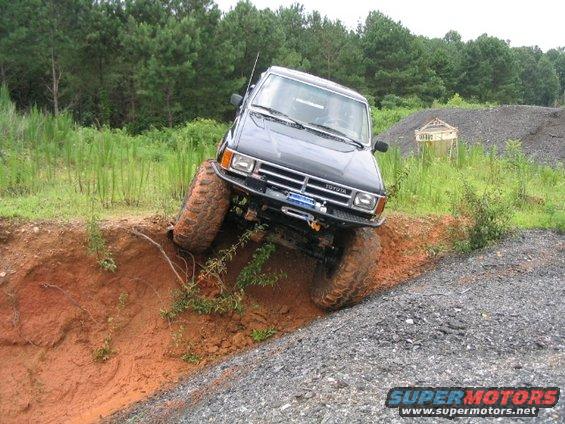 Black Toyota pickup truck with large tires navigating a steep dirt embankment