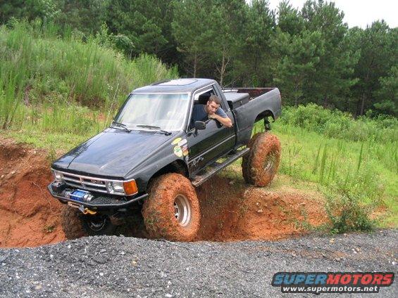 Black Toyota pickup truck with large tires navigating a dirt obstacle