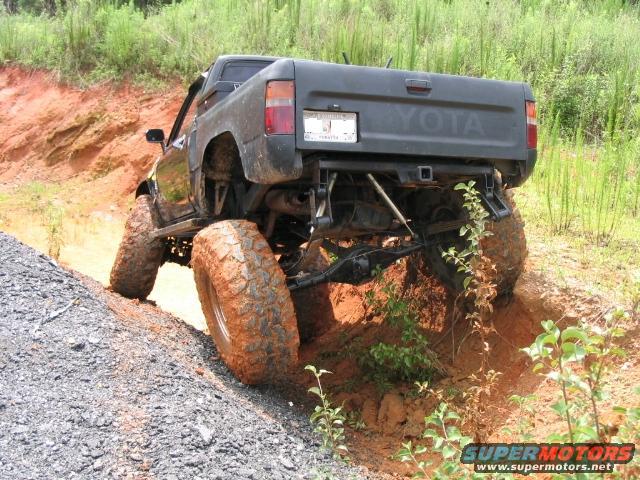 1989 Toyota pickup truck with large tires climbing a dirt hill