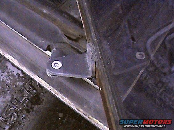 Close-up of a black metal door hinge bracket attached to a metal frame