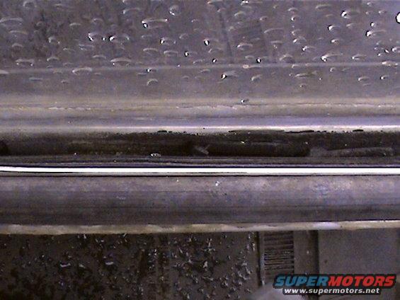 Close-up of a vehicle's door sill with water droplets on the window above
