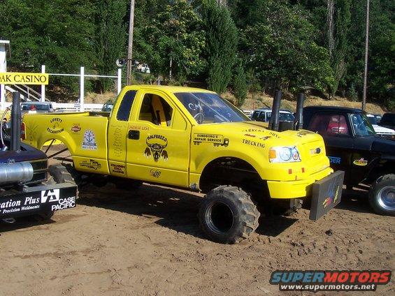 Yellow 2004 Ford F-150 with large tires and dual exhaust stacks