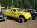 1994 Ford F-150 - This modified yellow Ford F-150 features oversized tires, dual exhaust stacks, and custom decals.