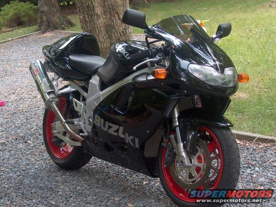 Black Suzuki motorcycle with red rims and Yoshimura exhaust parked on gravel