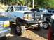 1994 Ford F-150 - A lifted white Ford F-150 pickup truck is parked next to other vehicles.