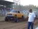 1994 Ford F-150 - A modified yellow pickup truck competes in a pull event, with a spectator observing the action.