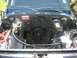 1979 Chevrolet C/K Pickup - The engine bay of a blue 1979 Chevrolet C/K Pickup shows exposed wiring and various engine components.