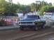 1994 Ford F-150 - A lifted green Ford pickup truck competes in an event on a dirt track, with spectators in the background.
