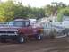 1994 Ford F-150 - A red pickup truck competes in a pull event, dragging a trailer with "TERMINATOR" written on its side.
