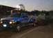 1994 Ford F-150 - A blue pickup truck with custom graphics is seen in a pull event, with a weight sled behind it.