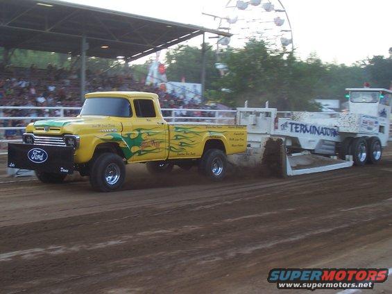 Yellow 1959 Ford pickup truck with flames pulling a sled labeled "Terminator"