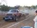 1994 Ford F-150 - Modified pickup truck competes in a pull event, kicking up dust as it tows a trailer.