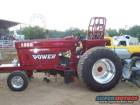 Red tractor with "POWER TRIP" and "1066 INTERNATIONAL" text, large rear tires, and a roll cage