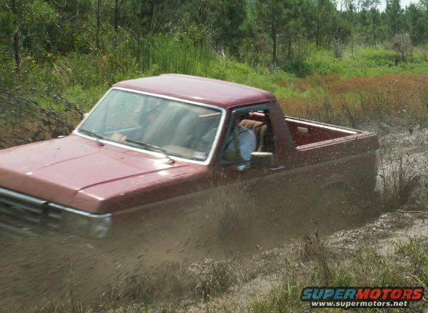 Red pickup truck in mud. The vehicle appears to be a 1987 Ford F-150